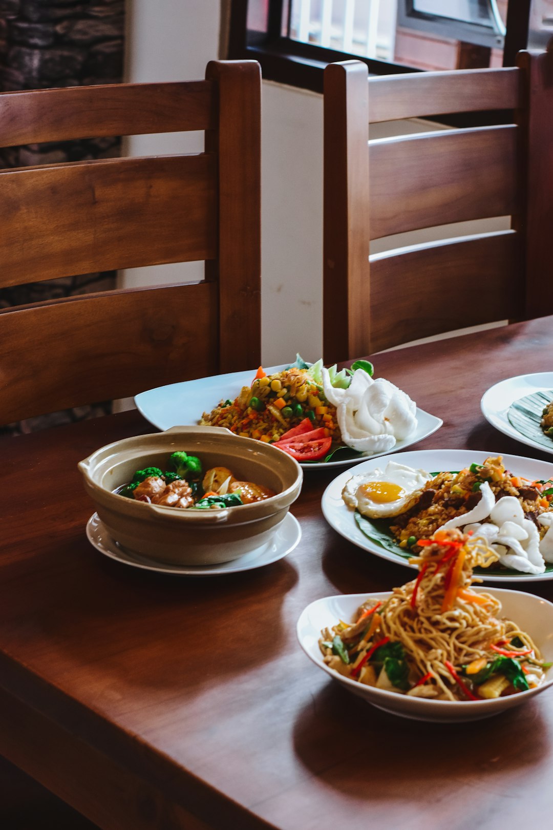 a-wooden-table-topped-with-plates-of-food-rmciuwwxdb4